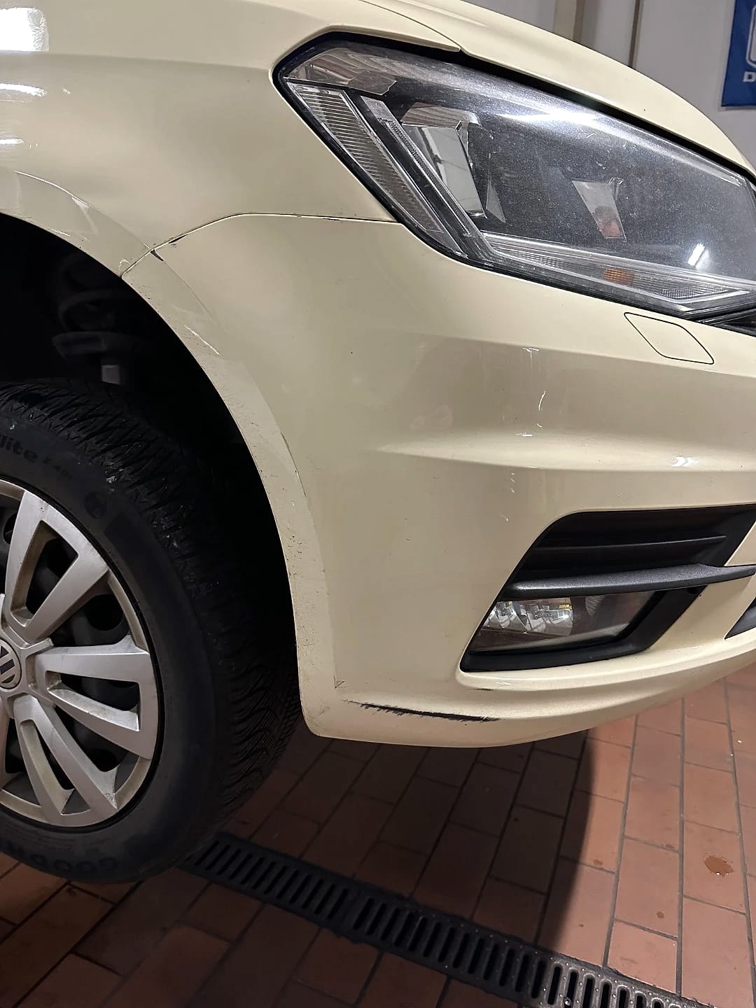 Beschädigte Front eines beigen VW Golf mit Delle und Lackabrieb an der Stoßstange