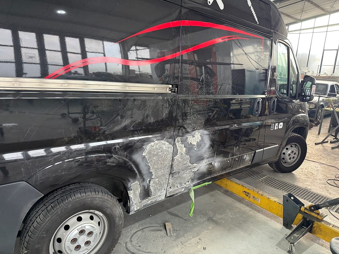 Schwarzer Transporter von Car Ferreira auf der Hebebühne, Seitenwand gespachtelt und zum Schleifen vorbereitet